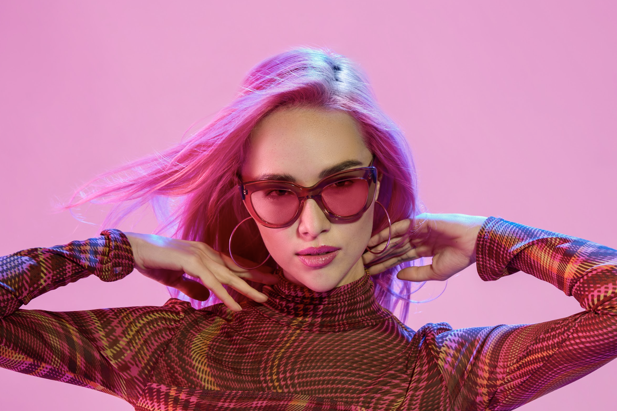 Woman wearing oversized sunglasses and a vibrant patterned turtleneck